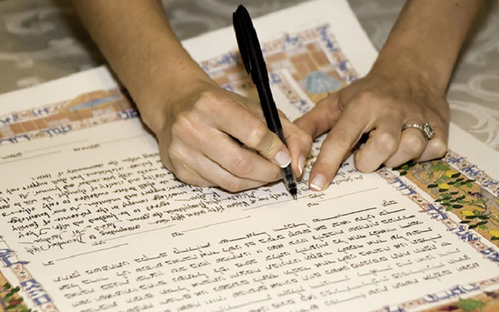 bride signing a jewish katuba marraige certificate